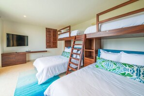 A bedroom with bunk beds, a TV, a wooden cabinet, and a blue rug. - Condo Las Olas in Punta Mita (Punta de Mita)