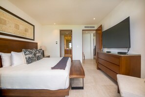 Ett modernt hotellrum med en stor säng, en träbänk, en platt-TV och en byrå i trä.