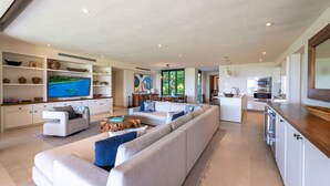 A spacious living area with a large flat-screen TV, a sofa, a dining table, and a kitchen area. - Condo Aquila in Punta Mita (Punta de Mita)