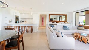 A modern kitchen with white cabinetry, a central island, and pendant lighting. - Condo Aquila in Punta Mita (Punta de Mita)