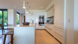 A modern kitchen with a central island, stainless steel appliances, and pendant lighting. - Condo Aquila in Punta Mita (Punta de Mita)