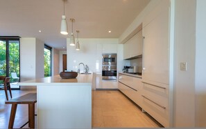 A modern kitchen with a central island, stainless steel appliances, and pendant lighting. - Condo Aquila in Punta Mita (Punta de Mita)