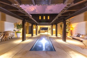 A traditional Japanese-style interior with a tatami mat floor, wooden beams, and a view into a room with a sofa and plants. - Estate La Sierra in Punta Mita (Punta de Mita)