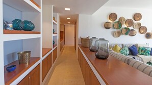 A hallway with wooden cabinets, shelves with decorative items, a sofa with cushions, and a wall with woven baskets. - Condo Terramar in Punta Mita (Punta de Mita)