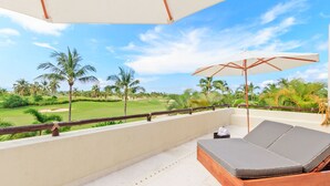 A balcony with a wooden bench and a large umbrella, overlooking a golf course with palm trees. - Condo Terramar in Punta Mita (Punta de Mita)
