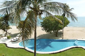 A swimming pool with a curved design, surrounded by palm trees and a sandy beach. - Condo Clavel in Punta Mita (Punta de Mita)