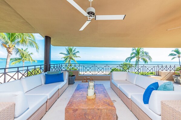 An outdoor seating area with white sofas, a table with candles, and a view of the ocean. - Condo Clavel in Punta Mita (Punta de Mita)