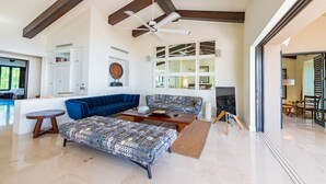 A spacious living area with a blue sofa, patterned ottoman, and a ceiling fan. - Condo Clavel in Punta Mita (Punta de Mita)