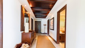 A hallway with a wooden ceiling, a rug, a wooden bench, a basket of rolled towels, and a mirror on the wall. - Condo Clavel in Punta Mita (Punta de Mita)