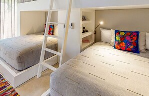 A room with two beds, a ladder, a shelf with books, and a colorful blanket. - Villa Aurora in Punta Mita (Punta de Mita)