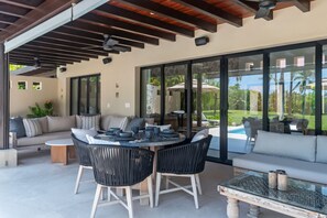Eine Terrasse im Freien mit einem runden Tisch, schwarzen Stühlen, einer Couch und einem Couchtisch mit Glasplatte.