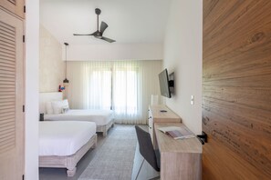Une chambre d’hôtel avec deux lits, un bureau, une chaise, une télévision et un ventilateur de plafond.
