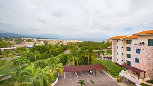 A hotel with a parking area, palm trees, and a view of the city and ocean. - Condo Gerbera in Punta Mita (Punta de Mita)