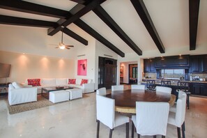 A spacious living area with a white sofa set, a wooden dining table with chairs, and a kitchen in the background. - Condo Gerbera in Punta Mita (Punta de Mita)