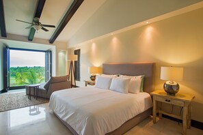 A bedroom with a large bed, two bedside tables with lamps, a ceiling fan, and a view of greenery outside. - Condo Gerbera in Punta Mita (Punta de Mita)