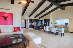 A spacious living area with a white sofa, a coffee table, and a dining area with chairs and a table. - Condo Gerbera in Punta Mita (Punta de Mita)