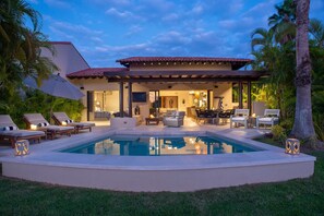 A poolside area with lounge chairs, a pool, and a covered patio with seating. - Villa Tamayo in Punta Mita (Punta de Mita)