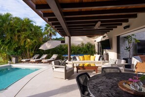 A poolside area with lounge chairs, a sofa, and a table. - Villa Tamayo in Punta Mita (Punta de Mita)