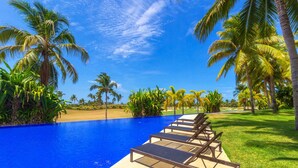 A pool with lounge chairs, palm trees, and a clear blue sky. - Condo Palma Azul in Punta Mita (Punta de Mita)