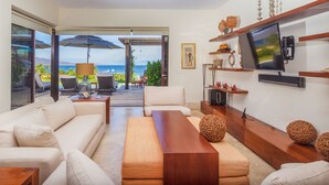 A modern living room with a sofa, coffee table, and TV. There is a balcony with a view of the ocean. - Villa Aguamarina in Punta Mita (Punta de Mita)