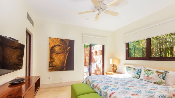 A bedroom with a bed, a green bench, a ceiling fan, a TV, and artwork on the walls. - Villa Aguamarina in Punta Mita (Punta de Mita)