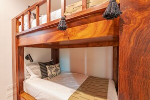 A bunk bed with a wooden headboard, a bedside lamp, and a patterned pillow. - Villa Mataiza in Punta Mita (Punta de Mita)