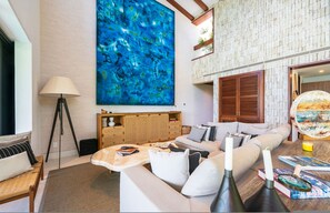 Un salon moderne avec un grand tableau abstrait, un ensemble de canapés, une table basse et une lampe.