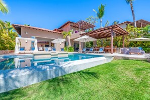 A swimming pool with lounge chairs and umbrellas, surrounded by a well-maintained lawn and palm trees. - Villa Diamante in Punta Mita (Punta de Mita)