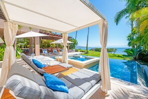A poolside area with lounge chairs, a pergola, and a view of the ocean. - Villa Diamante in Punta Mita (Punta de Mita)