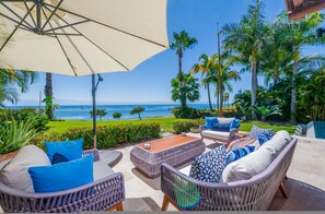 A patio with wicker furniture, a large umbrella, and a view of the ocean. - Villa Diamante in Punta Mita (Punta de Mita)