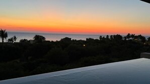 A poolside view at sunset with a clear sky, palm trees, and a distant horizon. - Condo Kumar in Punta Mita (Punta de Mita)