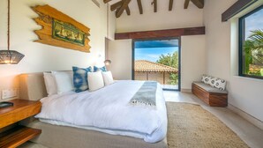 A bedroom with a large bed, a wooden headboard, a bench by the window, and a view of the outside. - Casa Marlago in Punta Mita (Punta de Mita)