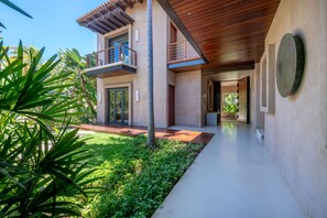Ein modernes, zweistöckiges Haus mit Balkon, Garten und einem Weg zum Eingang.