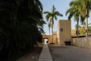 A pathway leading to a building with a clear view of the ocean, surrounded by palm trees and a gravel path. - Estate Jaguar in Punta Mita (Punta de Mita)