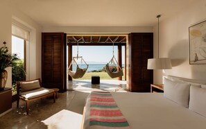 A bedroom with a bed, a hanging chair, a bedside table, a lamp, and a view of the sea. - Estate Jaguar in Punta Mita (Punta de Mita)