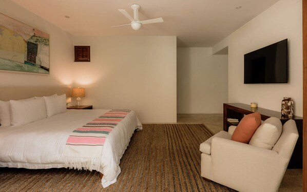 A bedroom with a bed, a desk, a chair, a television, and a ceiling fan. - Estate Jaguar in Punta Mita (Punta de Mita)