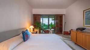 Une chambre d’hôtel moderne, dotée d’un grand lit, d’un bureau, d’une chaise, d’une plante en pot et offrant une vue sur l’extérieur.