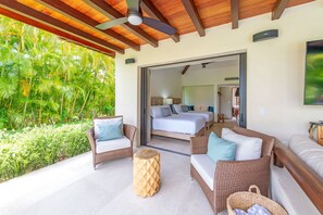 A balcony with wicker furniture, a wooden ceiling fan, and a view of lush greenery. - Villa Frida in Punta Mita (Punta de Mita)