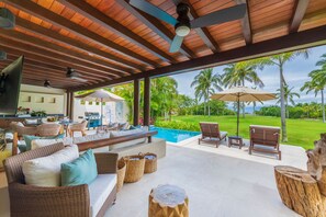 A covered outdoor area with a pool, lounge chairs, and a dining setup. - Villa Frida in Punta Mita (Punta de Mita)