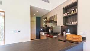 Une cuisine moderne avec des meubles en bois, une cuisinière encastrée et un plan de travail surmonté d’un saladier en bois.