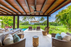 A covered outdoor area with wicker furniture, a pool, and palm trees. - Villa Frida in Punta Mita (Punta de Mita)