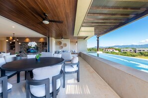 A modern outdoor dining area with a pool view, wooden ceiling, and a stone wall. - Condo Sardan in Punta Mita (Punta de Mita)