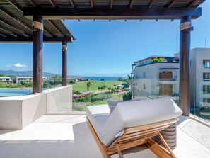 Ein Balkon mit Blick auf einen Golfplatz und den Ozean.