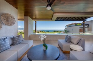 Ein modernes Wohnzimmer mit rundem Tisch, Sofas und Blick auf den Ozean.