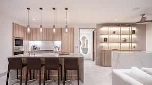 A modern kitchen with a central island, pendant lights, and a built-in shelving unit. - Condo La Joya in Punta Mita (Punta de Mita)