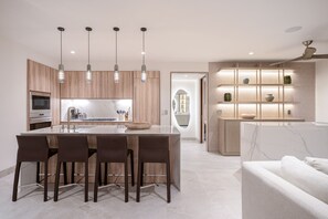 A modern kitchen with a central island, pendant lights, and a built-in shelving unit. - Condo La Joya in Punta Mita (Punta de Mita)