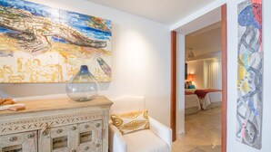 A room with a large abstract painting, a vase on a cabinet, and a bed with a red blanket. - Condo Ocean in Punta Mita (Punta de Mita)