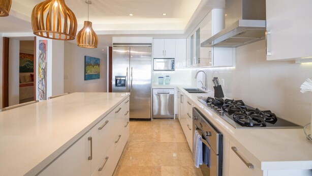A modern kitchen with a central island, stainless steel appliances, pendant lighting, and artwork on the walls. - Condo Ocean in Punta Mita (Punta de Mita)