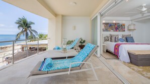A balcony with a lounge chair, a table with a vase, and a view of the beach. - Condo Ocean in Punta Mita (Punta de Mita)
