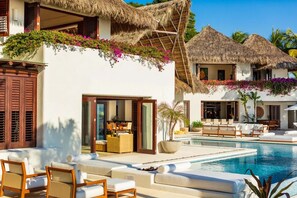 Ein Resort mit Pool, Sitzgelegenheiten im Freien und strohgedeckten Gebäuden.